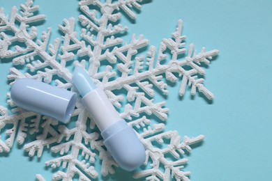 Photo of Moisturizing lip balm and Christmas decor on light blue background, flat lay. Winter care