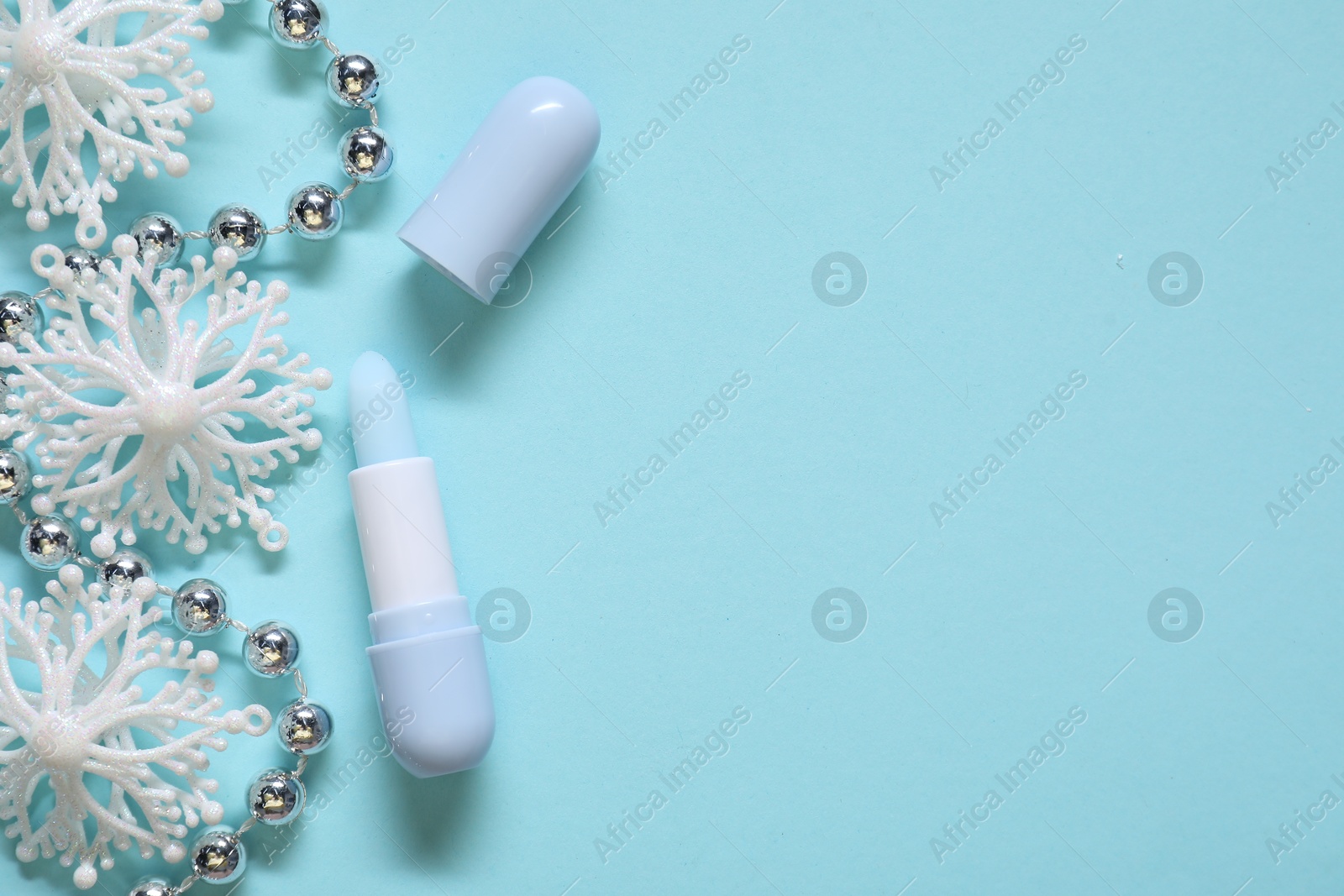 Moisturizing lip balm and Christmas decor on light blue background, flat lay. Space for text Photo of Moisturizing lip balm and Christmas decor on light blue background, flat lay. Space for text