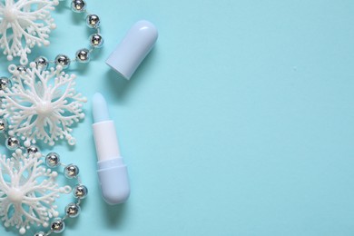 Photo of Moisturizing lip balm and Christmas decor on light blue background, flat lay. Space for text