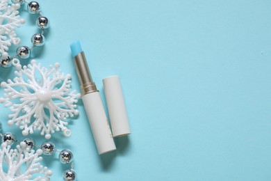 Photo of Moisturizing lip balm and Christmas decor on light blue background, flat lay. Space for text