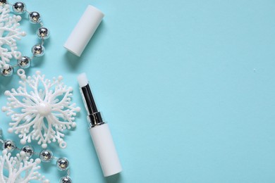 Photo of Moisturizing lip balm and Christmas decor on light blue background, flat lay. Space for text