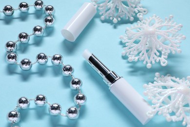 Photo of Moisturizing lip balm and Christmas decor on light blue background, above view. Winter care