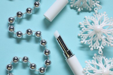 Photo of Moisturizing lip balm and Christmas decor on light blue background, flat lay. Winter care