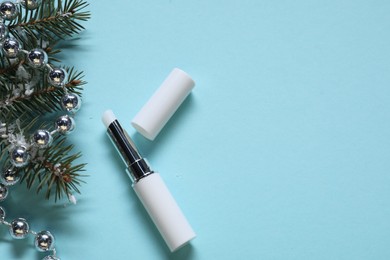 Photo of Moisturizing lip balm, Christmas decor and fir tree branches on light blue background, flat lay. Space for text