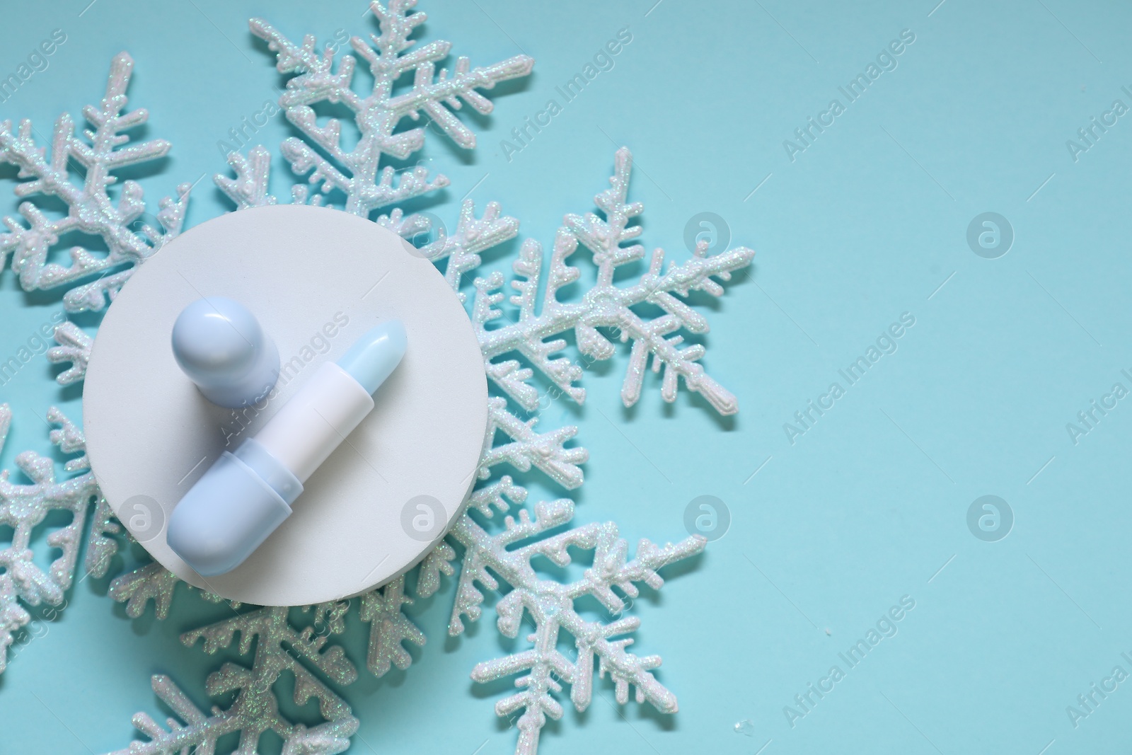 Moisturizing lip balm and Christmas decor on light blue background, flat lay. Space for text Photo of Moisturizing lip balm and Christmas decor on light blue background, flat lay. Space for text