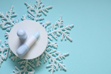 Photo of Moisturizing lip balm and Christmas decor on light blue background, flat lay. Space for text