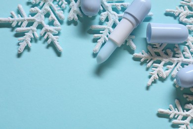 Photo of Moisturizing lip balms and Christmas decor on light blue background, flat lay. Space for text
