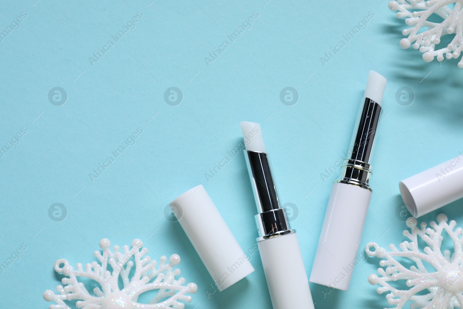 Moisturizing lip balms and Christmas decor on light blue background, flat lay. Space for text Photo of Moisturizing lip balms and Christmas decor on light blue background, flat lay. Space for text