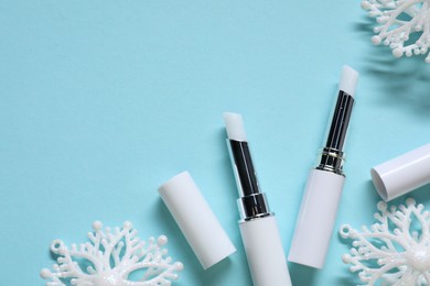 Photo of Moisturizing lip balms and Christmas decor on light blue background, flat lay. Space for text