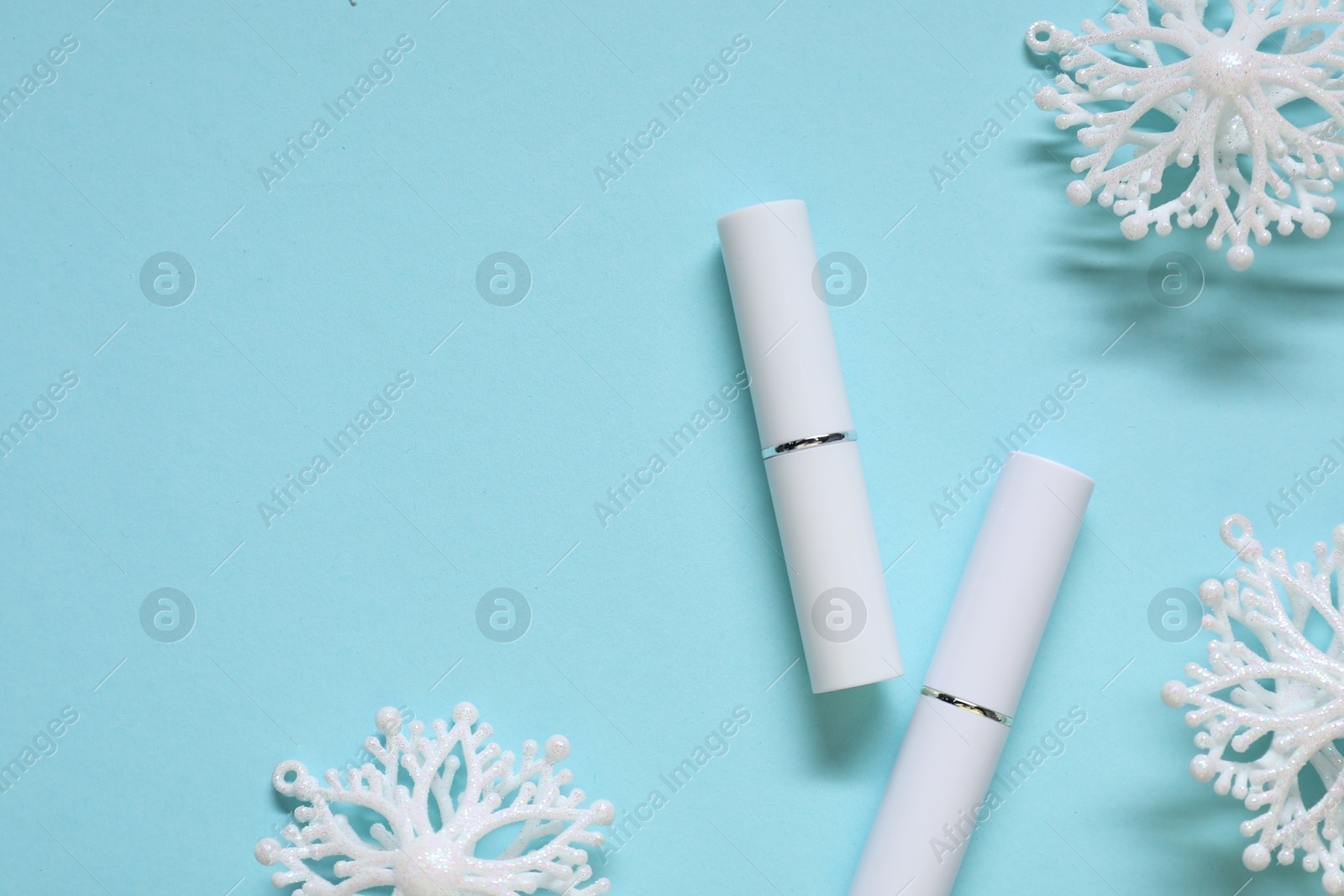 Moisturizing lip balms and Christmas decor on light blue background, flat lay. Space for text Photo of Moisturizing lip balms and Christmas decor on light blue background, flat lay. Space for text