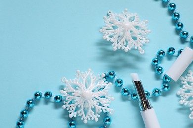 Photo of Moisturizing lip balm and Christmas decor on light blue background, flat lay. Space for text