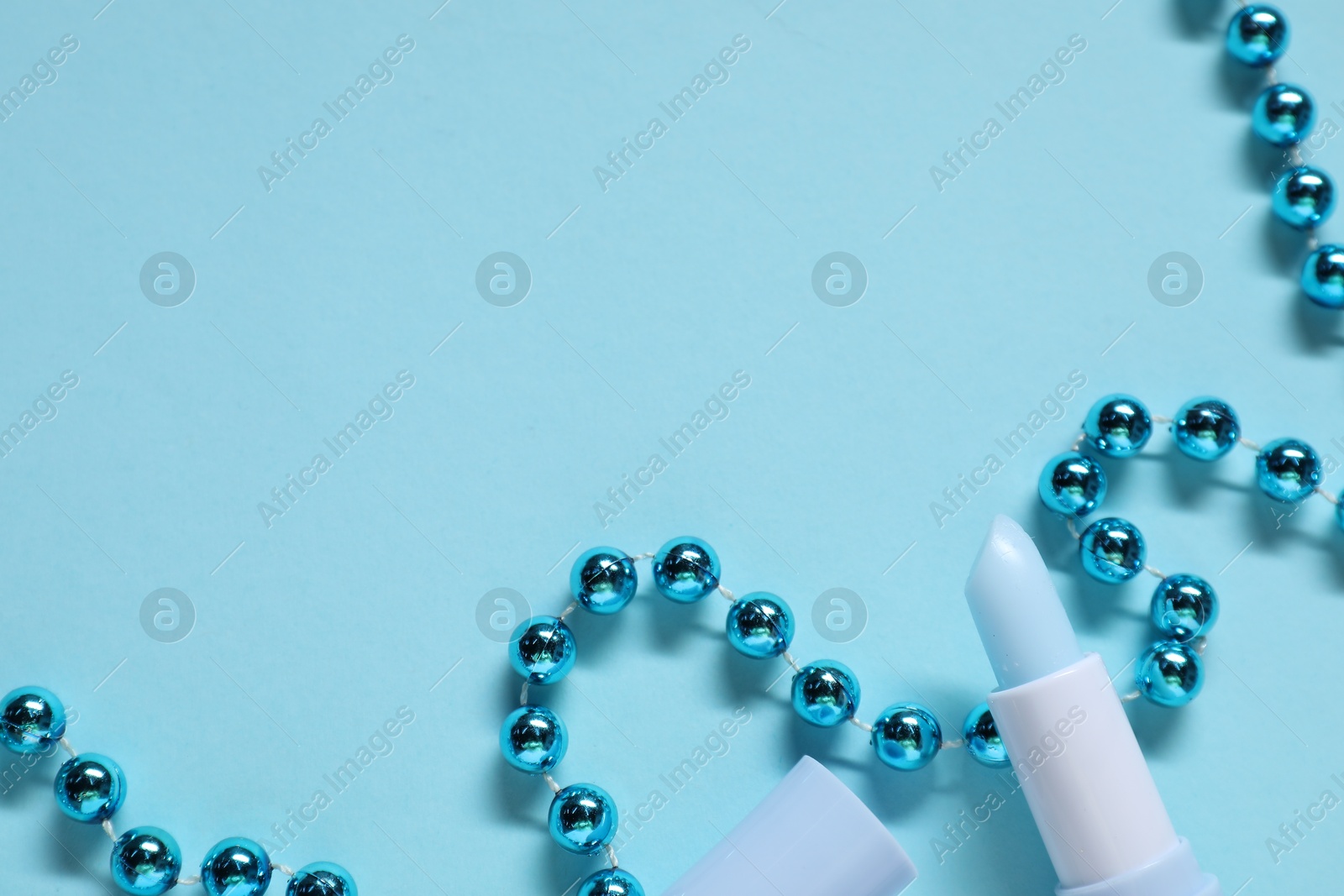 Photo of Moisturizing lip balm and Christmas decor on light blue background, flat lay. Space for text