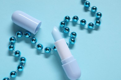 Photo of Moisturizing lip balm and Christmas decor on light blue background, flat lay. Winter care