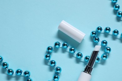 Photo of Moisturizing lip balm and Christmas decor on light blue background, flat lay. Space for text
