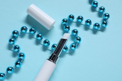 Photo of Moisturizing lip balm and Christmas decor on light blue background, flat lay. Winter care