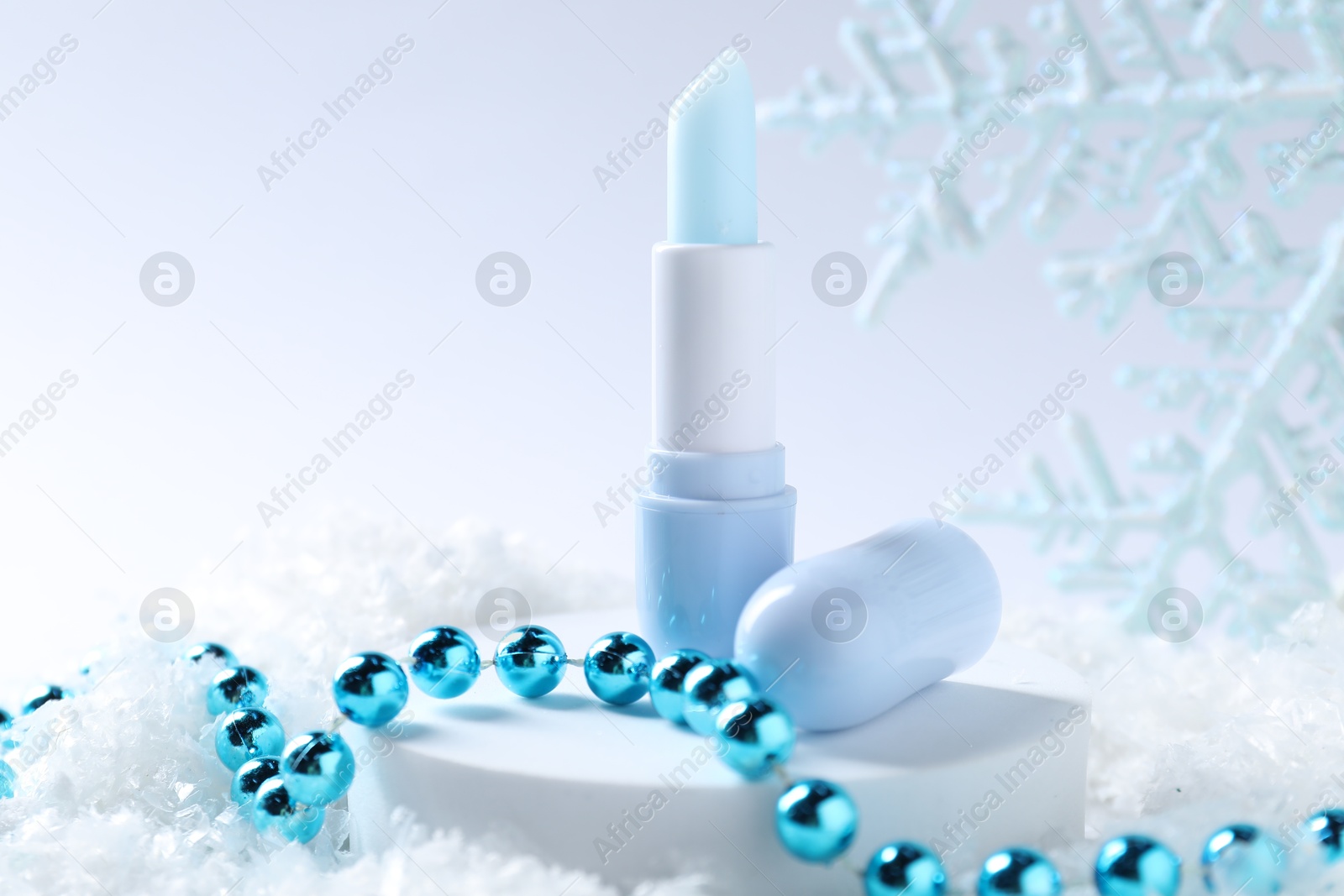 Moisturizing lip balm and Christmas decor on artificial snow, closeup. Winter care Photo of Moisturizing lip balm and Christmas decor on artificial snow, closeup. Winter care
