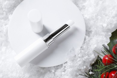Photo of Moisturizing lip balm and Christmas decor on artificial snow, flat lay. Winter care