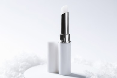 Photo of Moisturizing lip balm on artificial snow, closeup. Winter care