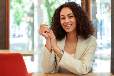 Photo of Portrait of smiling Latin American woman at table in cafe