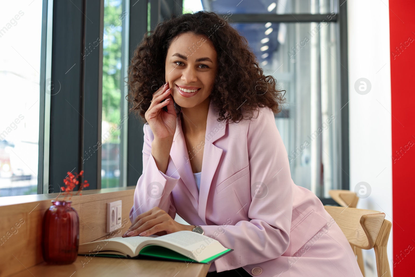 Portrait of smiling Latin American woman reading book in cafe Photo of Portrait of smiling Latin American woman reading book in cafe
