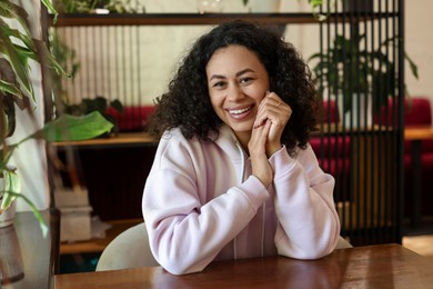 Photo of Portrait of smiling Latin American woman at table in cafe