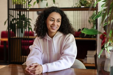 Photo of Portrait of smiling Latin American woman at table in cafe