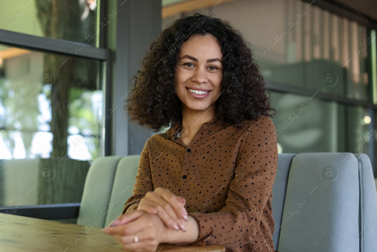 Portrait of smiling Latin American woman at table in cafe Photo of Portrait of smiling Latin American woman at table in cafe