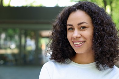 Photo of Portrait of smiling Latin American woman outdoors. Space for text