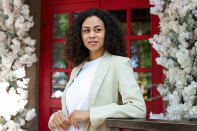 Photo of Portrait of smiling Latin American woman near building outdoors