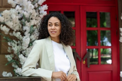 Photo of Portrait of smiling Latin American woman near building outdoors. Space for text