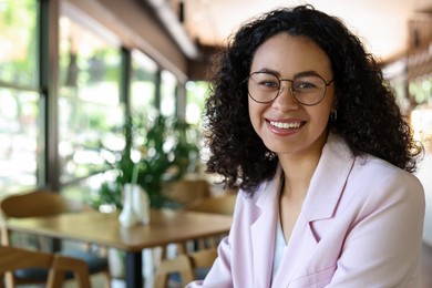 Photo of Portrait of smiling Latin American woman in cafe. Space for text