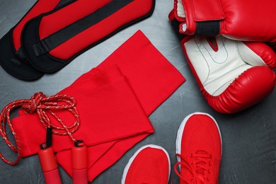 Photo of Sportswear, sneakers, boxing gloves, skipping rope and ankle weights on grey background, flat lay