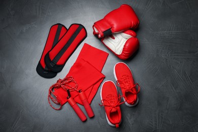 Photo of Sportswear, sneakers, boxing gloves, skipping rope and ankle weights on grey background, flat lay