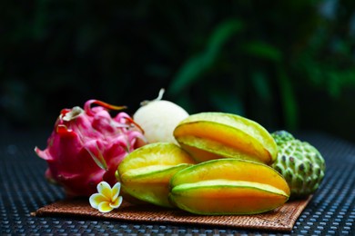 Photo of Different tropical fruit on wicker table outdoors, closeup. Space for text