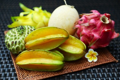 Photo of Different tropical fruit on wicker table, closeup