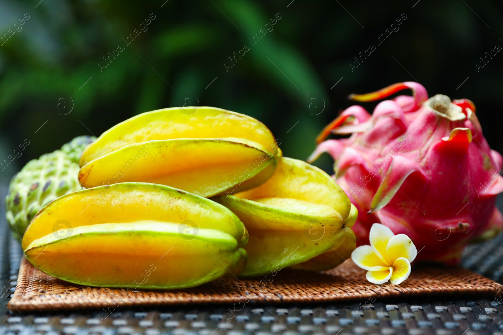 Different tropical fruit on wicker table outdoors, closeup Photo of Different tropical fruit on wicker table outdoors, closeup