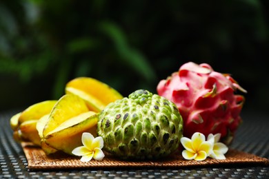 Photo of Different tropical fruit on wicker table outdoors, closeup. Space for text