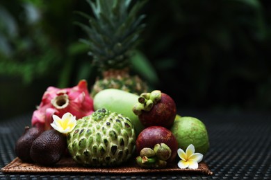 Photo of Different tropical fruit on wicker table outdoors. Space for text