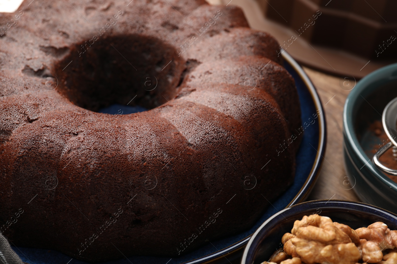 Tasty chocolate bundt cake and walnuts on table, closeup Photo of Tasty chocolate bundt cake and walnuts on table, closeup