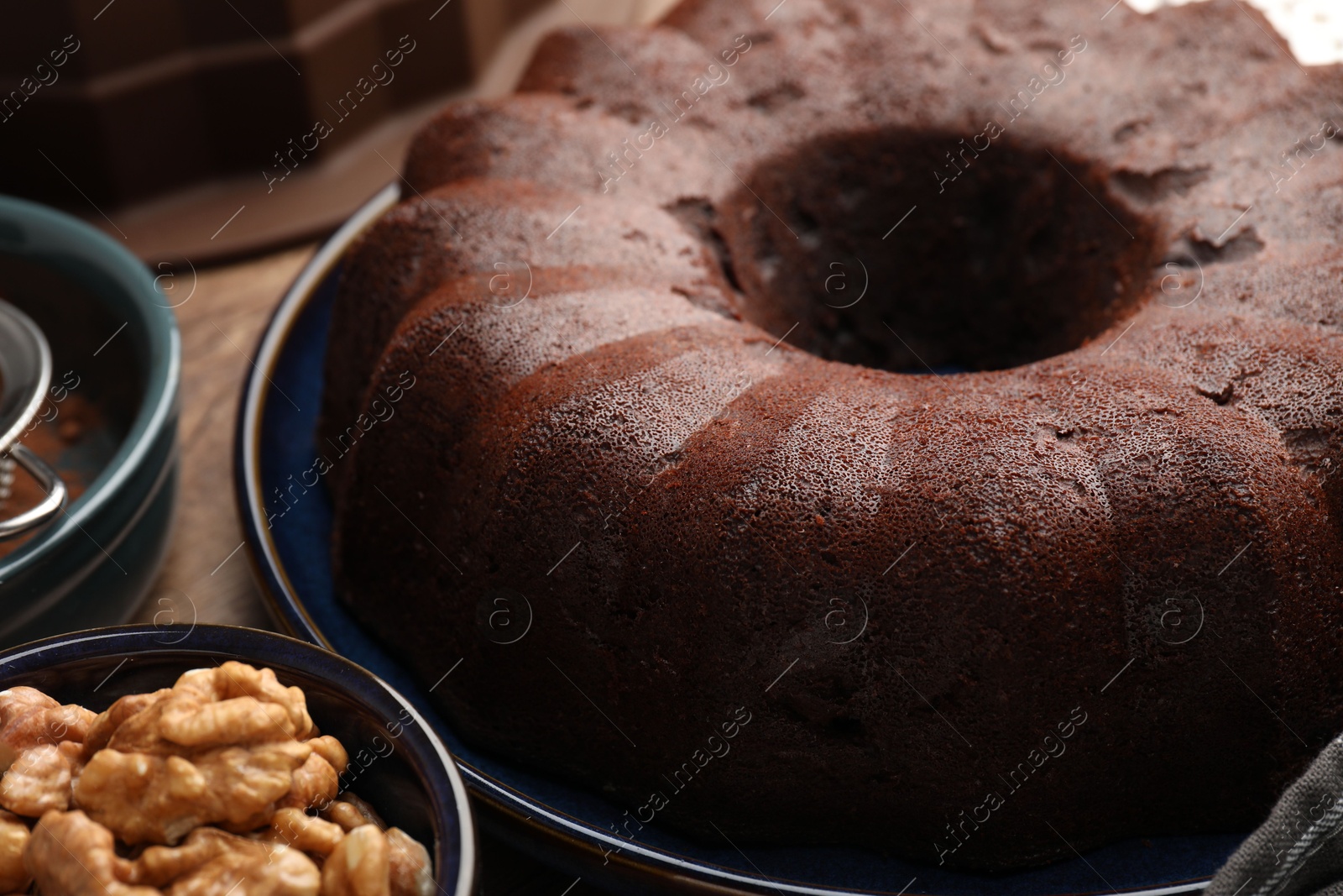 Tasty chocolate bundt cake and walnuts on table, closeup Photo of Tasty chocolate bundt cake and walnuts on table, closeup