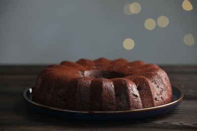 Photo of Tasty chocolate bundt cake on wooden table, closeup. Bokeh effect