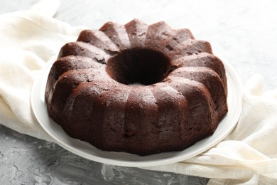 Photo of Tasty chocolate bundt cake on grey table, closeup