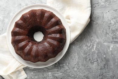 Photo of Tasty chocolate bundt cake on grey table, top view. Space for text
