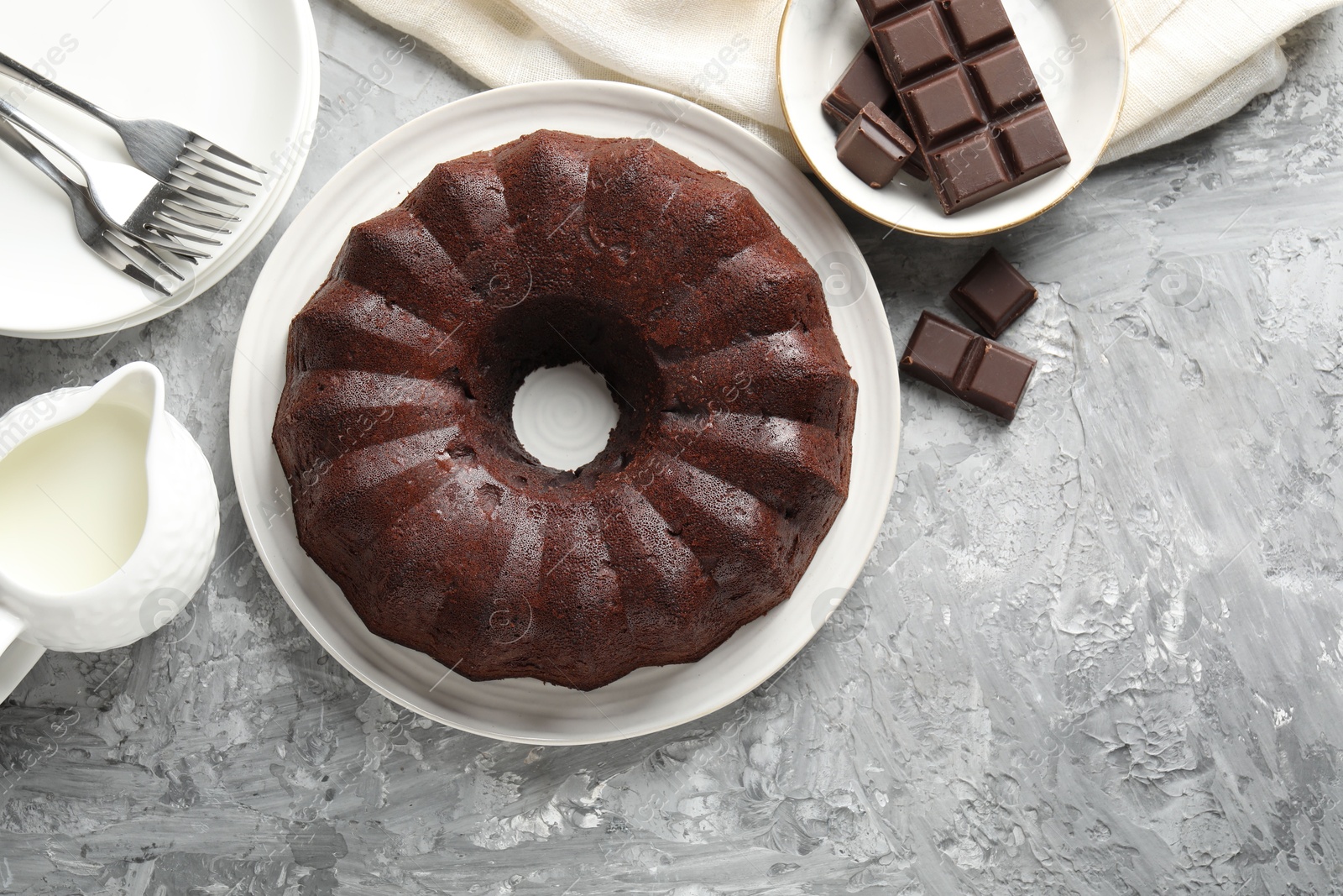 Tasty bundt cake, pieces of chocolate and milk on grey table, flat lay. Space for text Photo of Tasty bundt cake, pieces of chocolate and milk on grey table, flat lay. Space for text