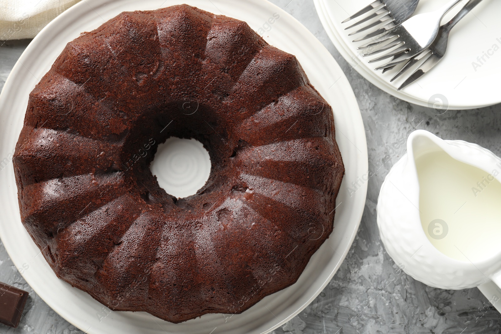 Tasty bundt cake, pieces of chocolate and milk on grey table, flat lay Photo of Tasty bundt cake, pieces of chocolate and milk on grey table, flat lay