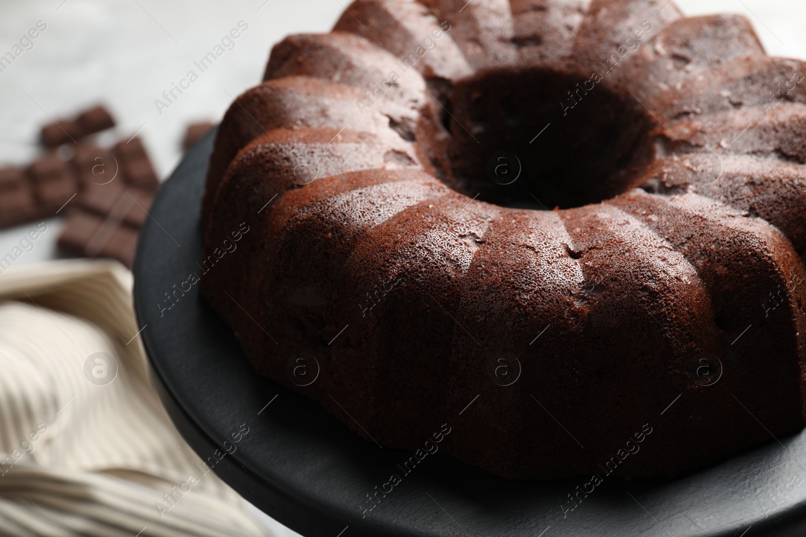 Tasty bundt cake and pieces of chocolate on table, closeup Photo of Tasty bundt cake and pieces of chocolate on table, closeup