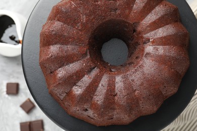 Photo of Tasty bundt cake, pieces of chocolate and sauce on table, flat lay