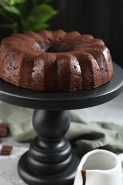 Photo of Tasty chocolate bundt cake and sauce on table, closeup