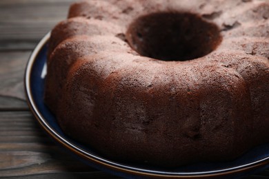 Photo of Tasty chocolate bundt cake on wooden table, closeup
