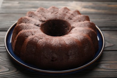 Photo of Tasty chocolate bundt cake on wooden table, closeup